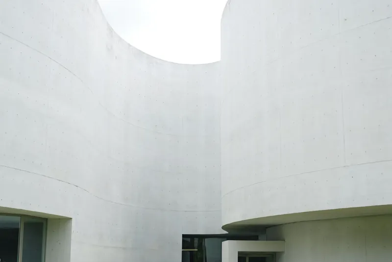 White curving walls of a minimalist museum around a lawn